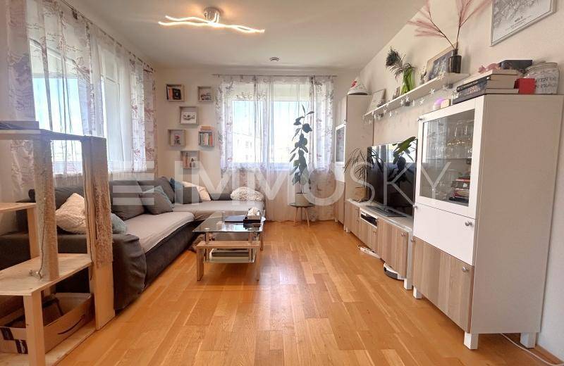 Geräumiges Wohnzimmer mit Holzboden, Sofa, TV-Möbeln und viel Tageslicht.