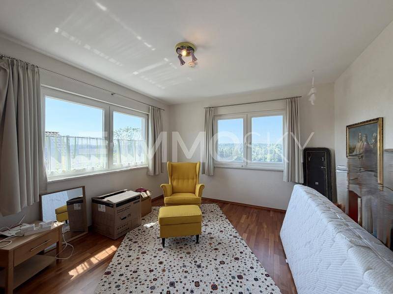Helles Schlafzimmer mit Holzboden, großen Fenstern und einem angenehmen Blick ins Grüne.