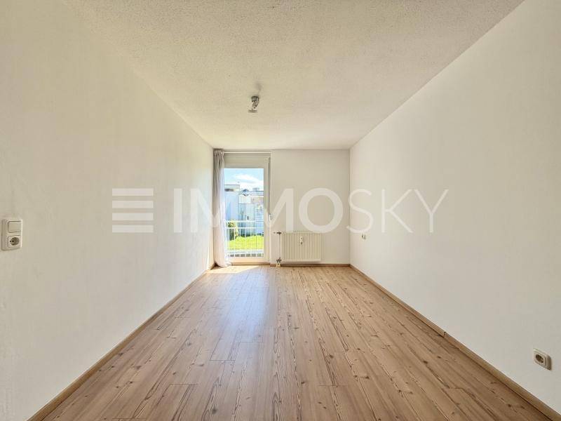 Helles Zimmer mit Holzdielenboden und direktem Zugang zum Garten, ideal als Schlaf- oder Arbeitszimmer.