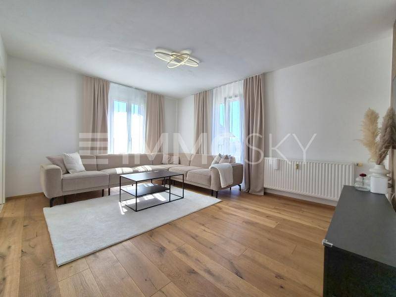 Gemütliches Wohnzimmer mit großem Ecksofa, Holzboden und viel natürlichem Licht.