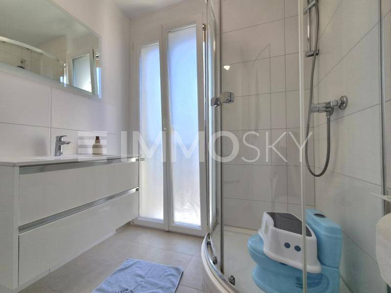 Modernes Badezimmer mit Dusche, Einzelwaschbecken und Fenster für Tageslicht.