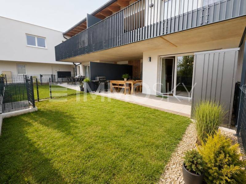 Modernes Mehrfamilienhaus mit Tiefgaragenzufahrt, Außenparkplätzen und gepflegter Grünfläche.