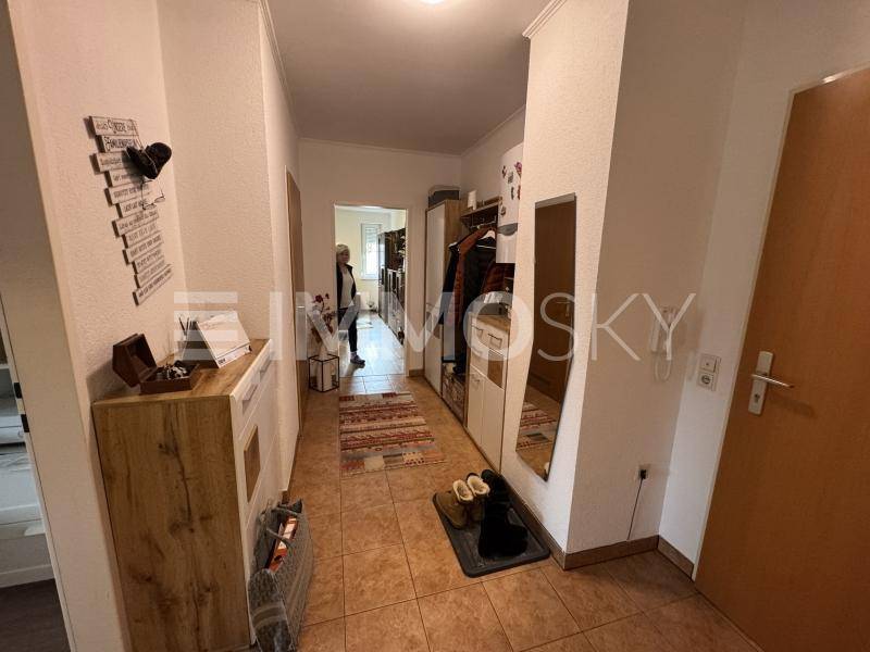 Heller Flur mit Fliesenboden, Garderobe und Spiegel, der zu weiteren Räumen führt.