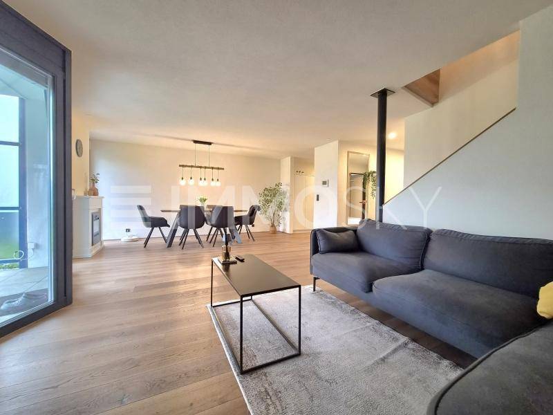 Heller offener Wohn- und Essbereich mit modernem Sofa, Holzboden und Zugang zum Außenbereich.