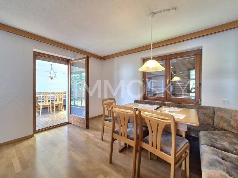 Gemütlicher Essbereich mit Holztisch, Eckbank und Zugang zu einem überdachten Balkon oder Terrasse.