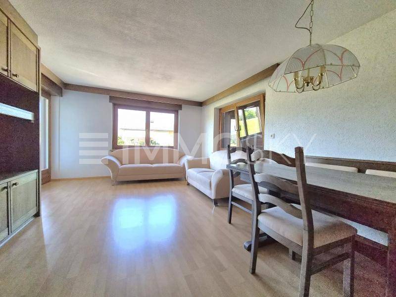 Heller Wohn- und Essbereich mit Parkettboden, beigen Sofas und traditionellem Esstisch mit Stühlen.