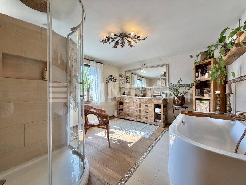 Geräumiges Badezimmer mit freistehender Badewanne, Duschkabine und Holzwaschtisch.