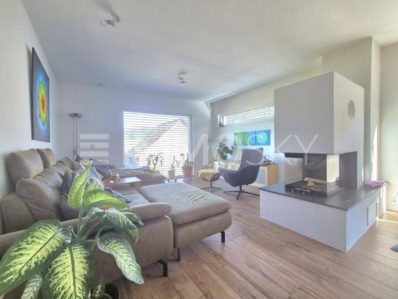 Helles Wohnzimmer mit modernem Kamin, großem Sofa und Holzboden.