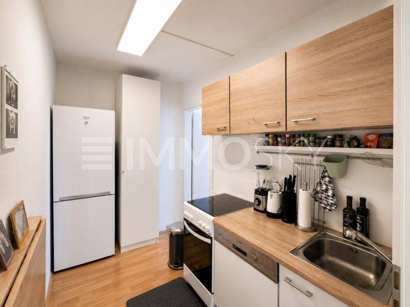 Kompakte Einbauküche mit Holzfronten, modernen Geräten und Spülbecken.