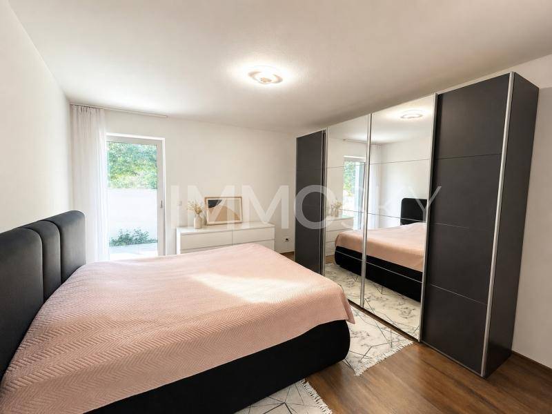 Helles Schlafzimmer mit großem Bett, Spiegelschränken und direktem Zugang zum Gartenbereich.