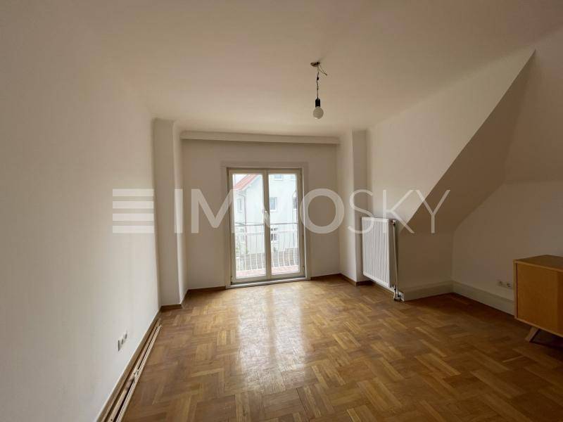 Schlafzimmer mit Fischgrätparkett, französischem Balkon und Dachschräge.