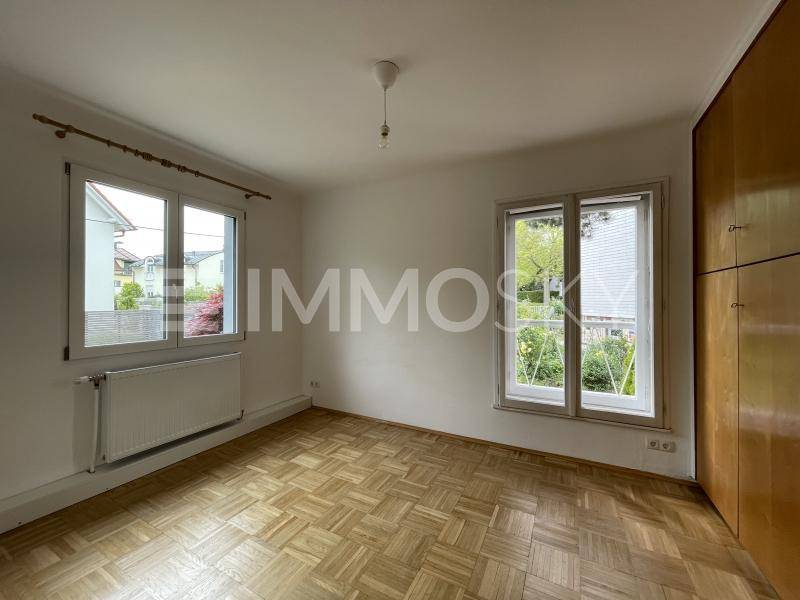 Helles Schlafzimmer mit Fischgrätparkett, Einbauschränken und Blick ins Grüne.
