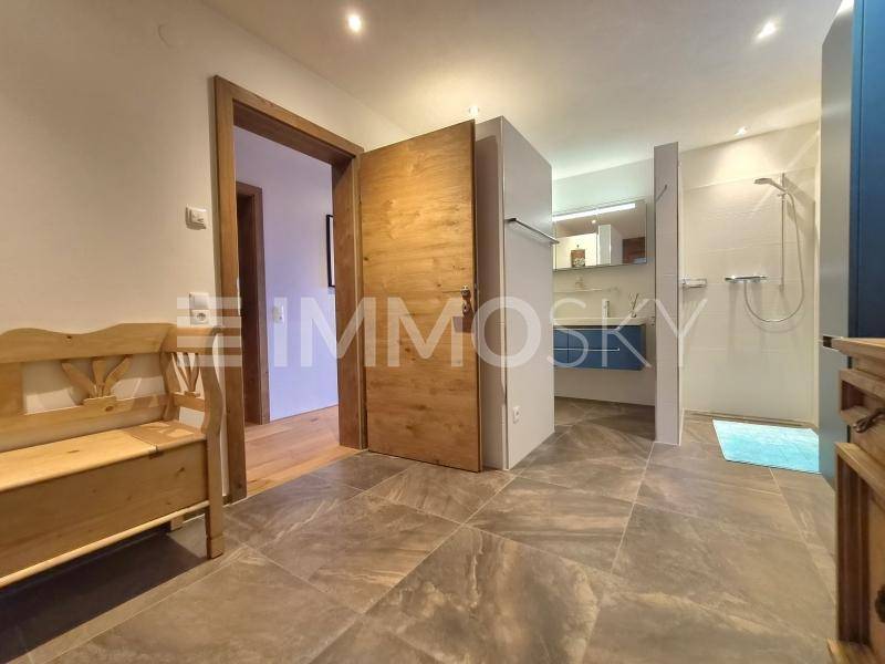 Modernes Badezimmer mit begehbarer Dusche, Fliesenboden und Holzelementen.