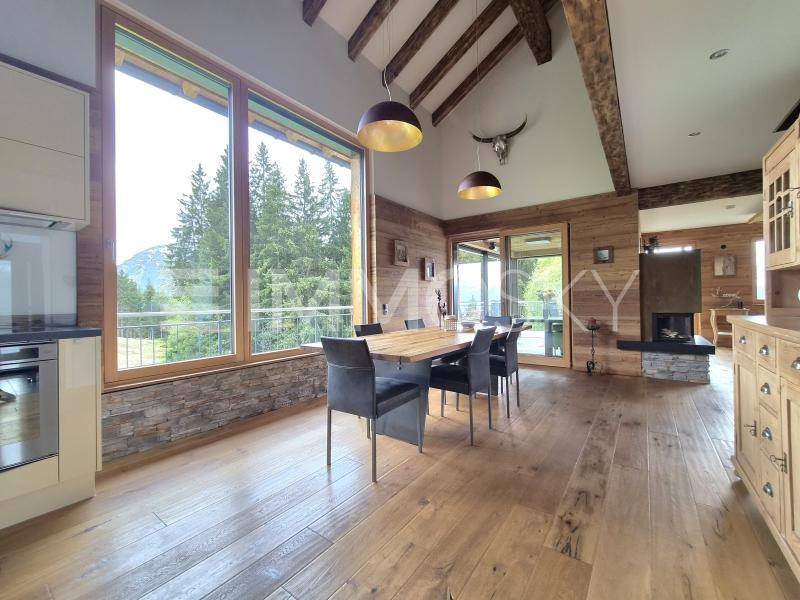 Heller Essbereich mit Holzboden, großen Fenstern und Blick auf die umliegende Natur.