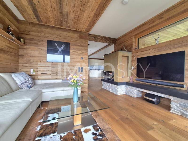 Gemütliches Wohnzimmer im alpinen Stil mit Holzwänden, Kamin und bequemer Couch.