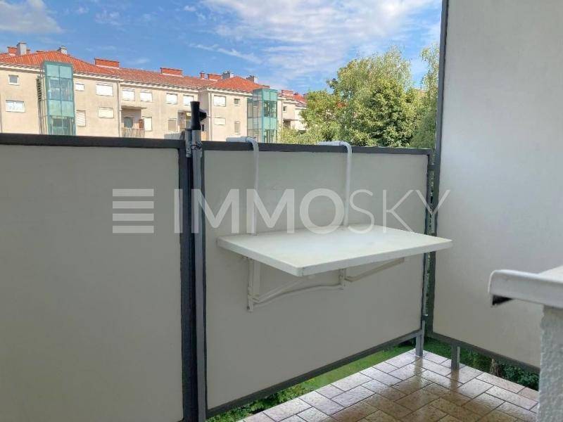 Kleiner Balkon mit einem Klapptisch und Blick auf die umliegende Wohnbebauung.