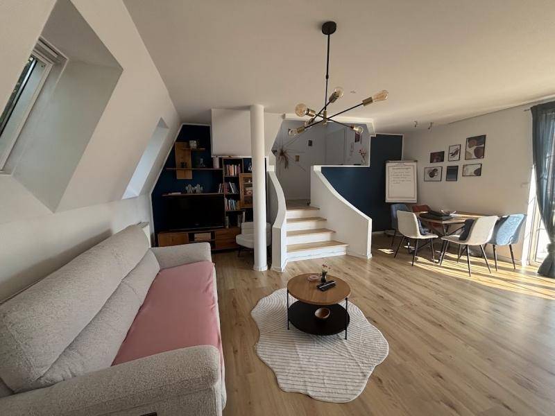 Gemütliches Wohnzimmer mit Dachschrägen, hellem Holzboden und einer eleganten Wendeltreppe.