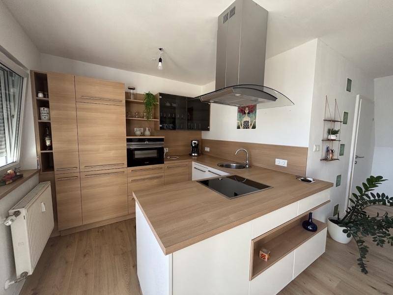 Moderne Einbauküche mit Holzfronten, Kochinsel und integrierten Geräten.