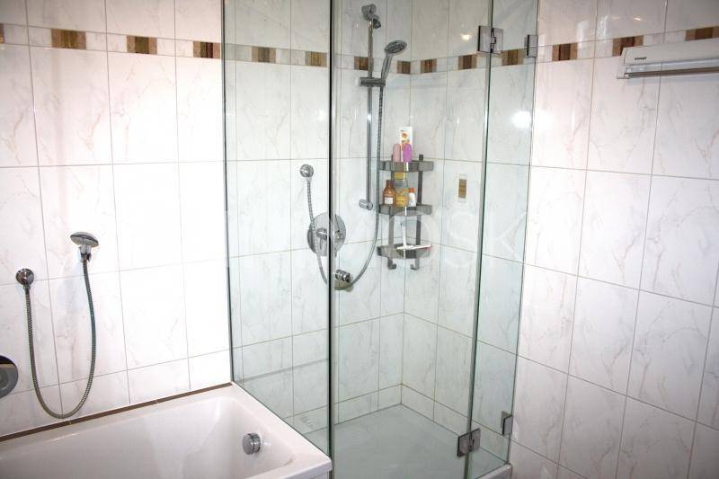 Modern gefliestes Badezimmer mit einer verglasten Duschkabine und einer Badewanne.