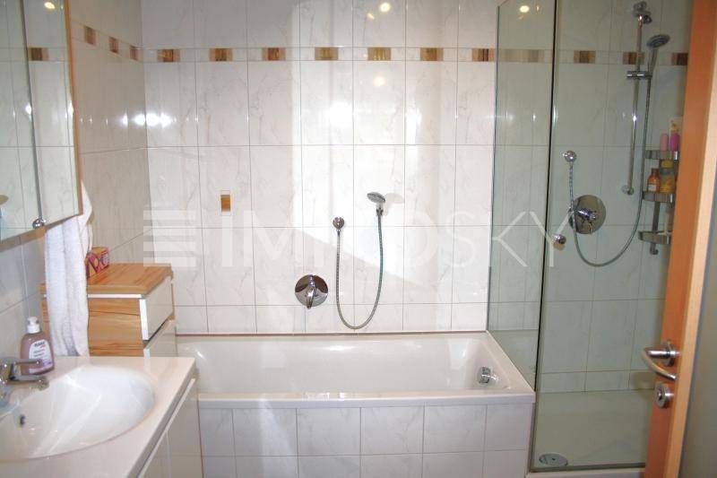 Funktionales Badezimmer mit Waschbecken, Spiegelschrank, Badewanne und separater Dusche.