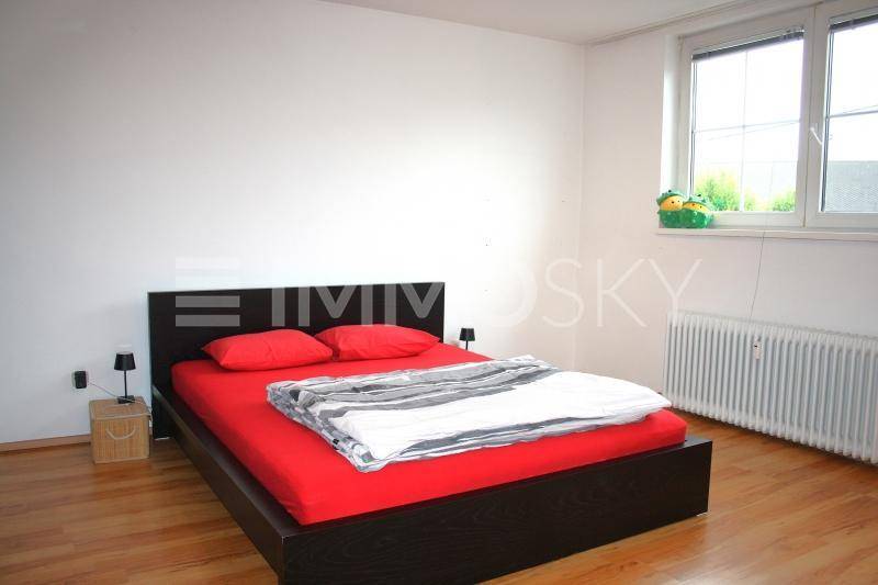 Helles Schlafzimmer mit Doppelbett, Holzboden und großem Fenster für viel Tageslicht.