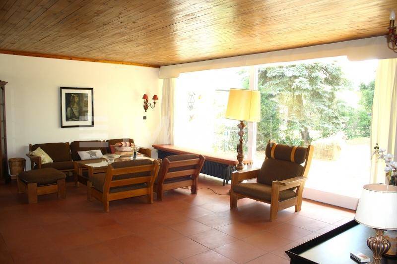 Geräumiges Wohnzimmer mit Terrakotta-Fliesen, Holzdecke und großen Fenstern zum Garten.