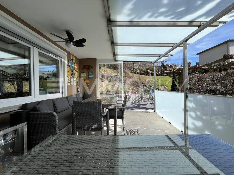 Geräumige überdachte Terrasse mit Essbereich und Lounge-Möbeln, ideal für gesellige Stunden.