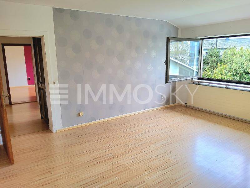 Geräumiger Innenraum mit Laminatboden und Fenster mit Blick ins Grüne.