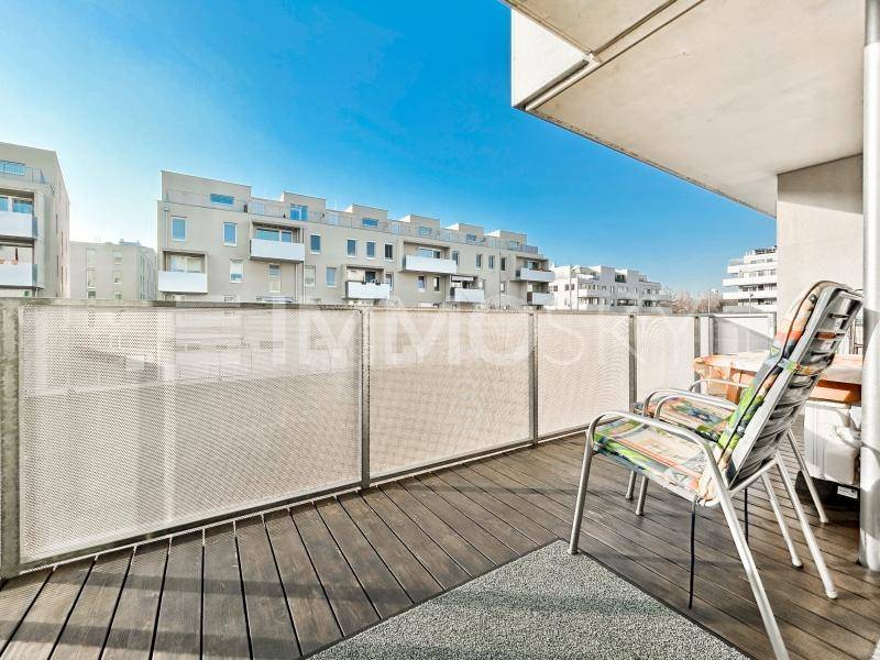 Sonniger Balkon mit Holzdielen und Stühlen, bietet einen weiten Blick auf die Umgebung.