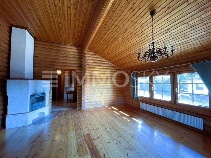 Helles Wohnzimmer mit Holzböden, Holzverkleidung, einem Kamin und einem Kronleuchter an der hohen Decke.