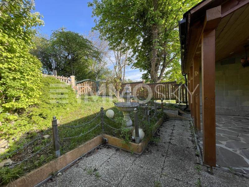 Gepflegter Gartenbereich mit gepflastertem Weg, einem Zierbrunnen und einer grünen Böschung.