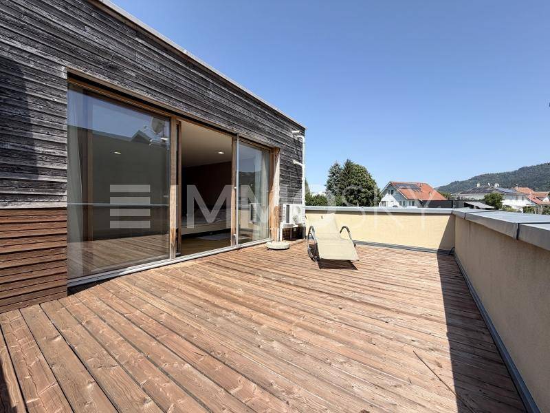 Große Holzterrasse mit Sonnenliege und weitem Blick über die Umgebung.