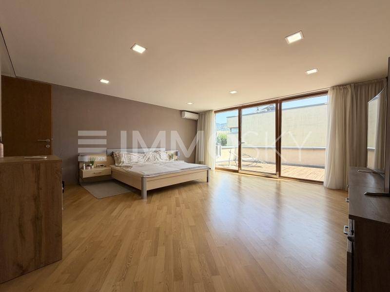 Helles Schlafzimmer mit Holzboden, großen Schiebetüren und Zugang zur Terrasse.