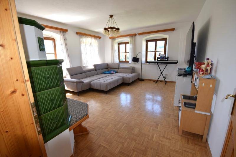 Gemütliches Wohnzimmer mit großem Sofa, traditionellem Kachelofen und Parkettboden.