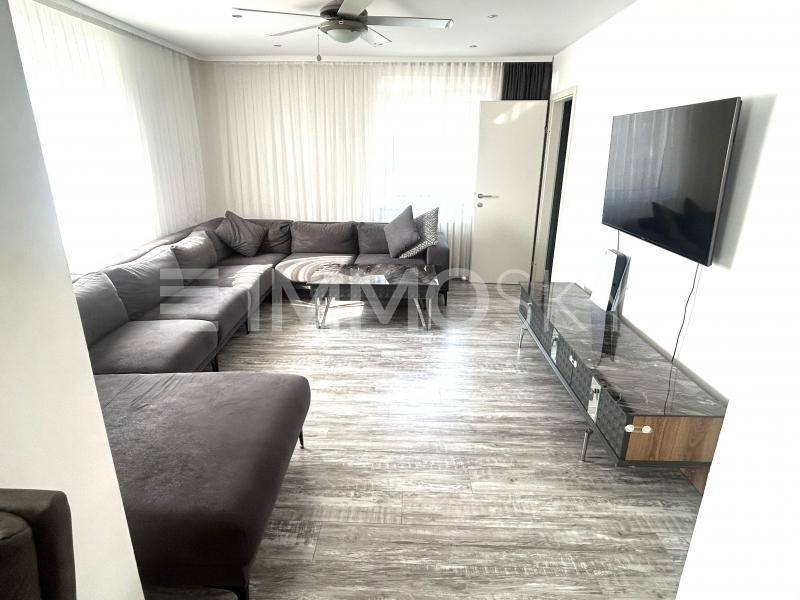 Heller Wohnbereich mit großem Ecksofa, Wandfernseher und modernem TV-Möbel.