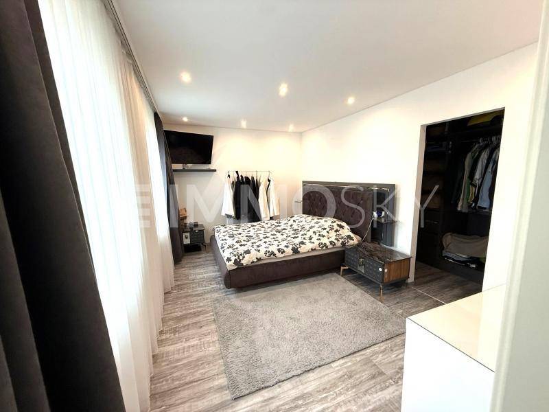 Modernes Schlafzimmer mit Doppelbett, integriertem Kleiderschrank und Holzoptikboden.