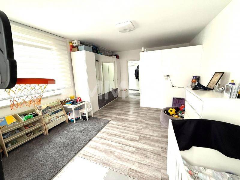 Kinderzimmer mit Babybett, Spielbereich und praktischen Aufbewahrungsmöbeln.