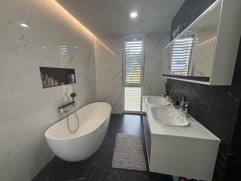 Modernes Badezimmer mit freistehender Badewanne, Doppelwaschbecken und eleganten Marmorfliesen.