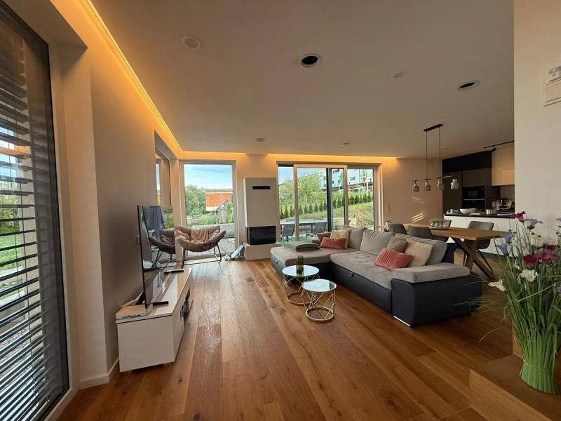Geräumiges Wohnzimmer mit großem Sofa, Kamin und offenem Übergang zum Essbereich.