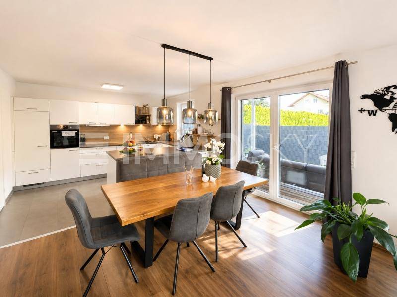 Heller offener Wohn- und Essbereich mit moderner Küche, Holztisch und Zugang zur Terrasse.