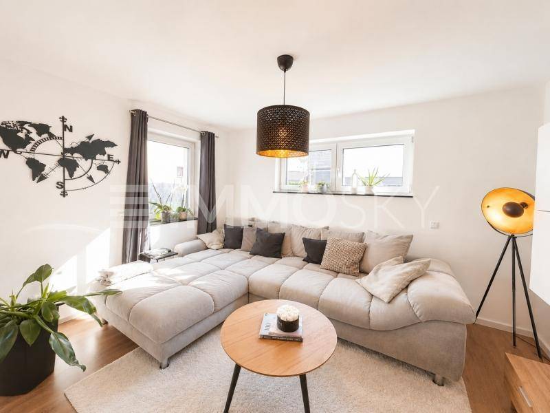 Gemütliches Wohnzimmer mit großem Ecksofa, Holzboden und moderner Dekoration.