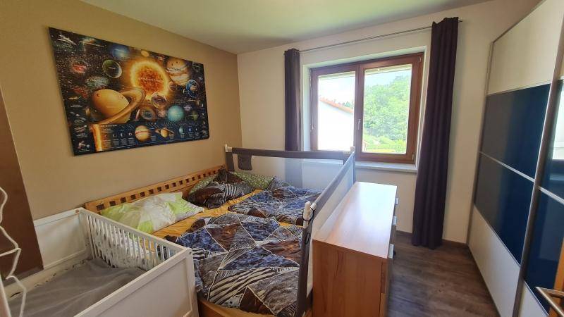 Kinderzimmer mit großem Bett, Babybett und Fenster mit Blick ins Grüne.