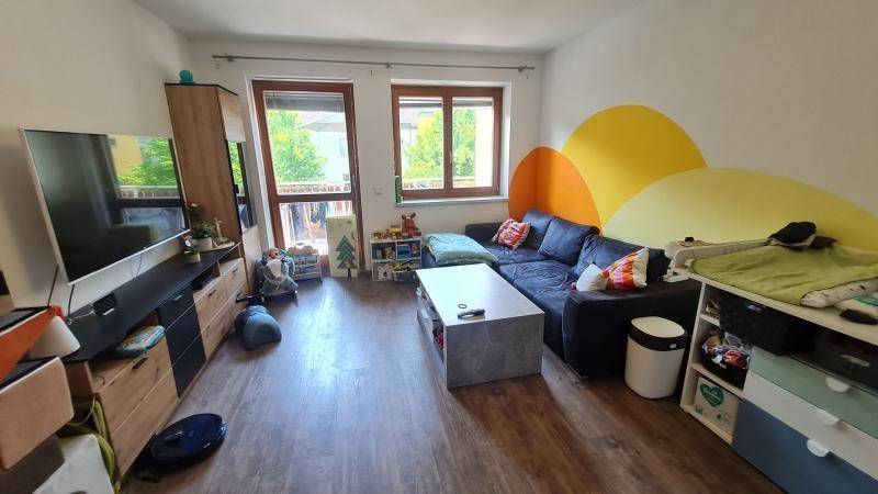 Helles Wohnzimmer mit Holzboden, gemütlichem Sofa und farbenfroher Wandgestaltung.