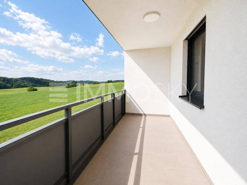 Geräumiger Balkon mit Fliesenboden und weitem, unverbautem Blick über grüne Felder.
