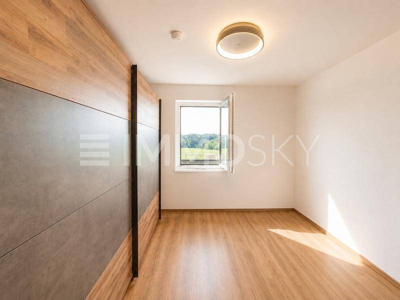 Helles Schlafzimmer mit Laminatboden, Einbauschrank und weitem Blick ins Grüne.