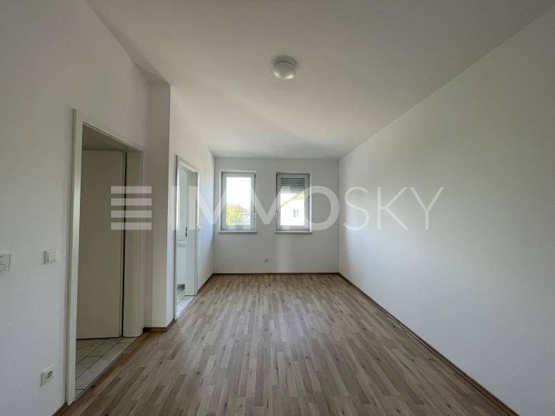 Helles Schlafzimmer mit Holzboden und zwei Fenstern, bereit zur individuellen Gestaltung.