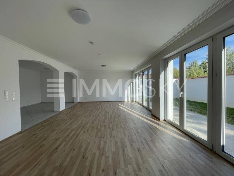 Großer, lichtdurchfluteter Wohnbereich mit Holzboden und Zugang zur Terrasse.