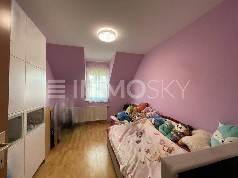 Gemütliches Kinderzimmer mit rosa Wänden, Holzboden und Dachschrägenfenster.