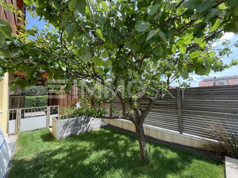 Kleiner, gepflegter Gartenbereich mit Baum und Holzzaun.