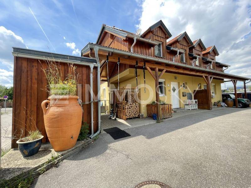 Außenansicht des Hauses mit Holzelementen und Zufahrt.